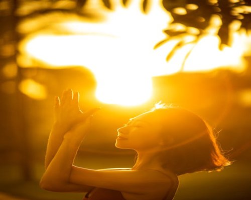 Woman practicing yoga outdoors in sunlight